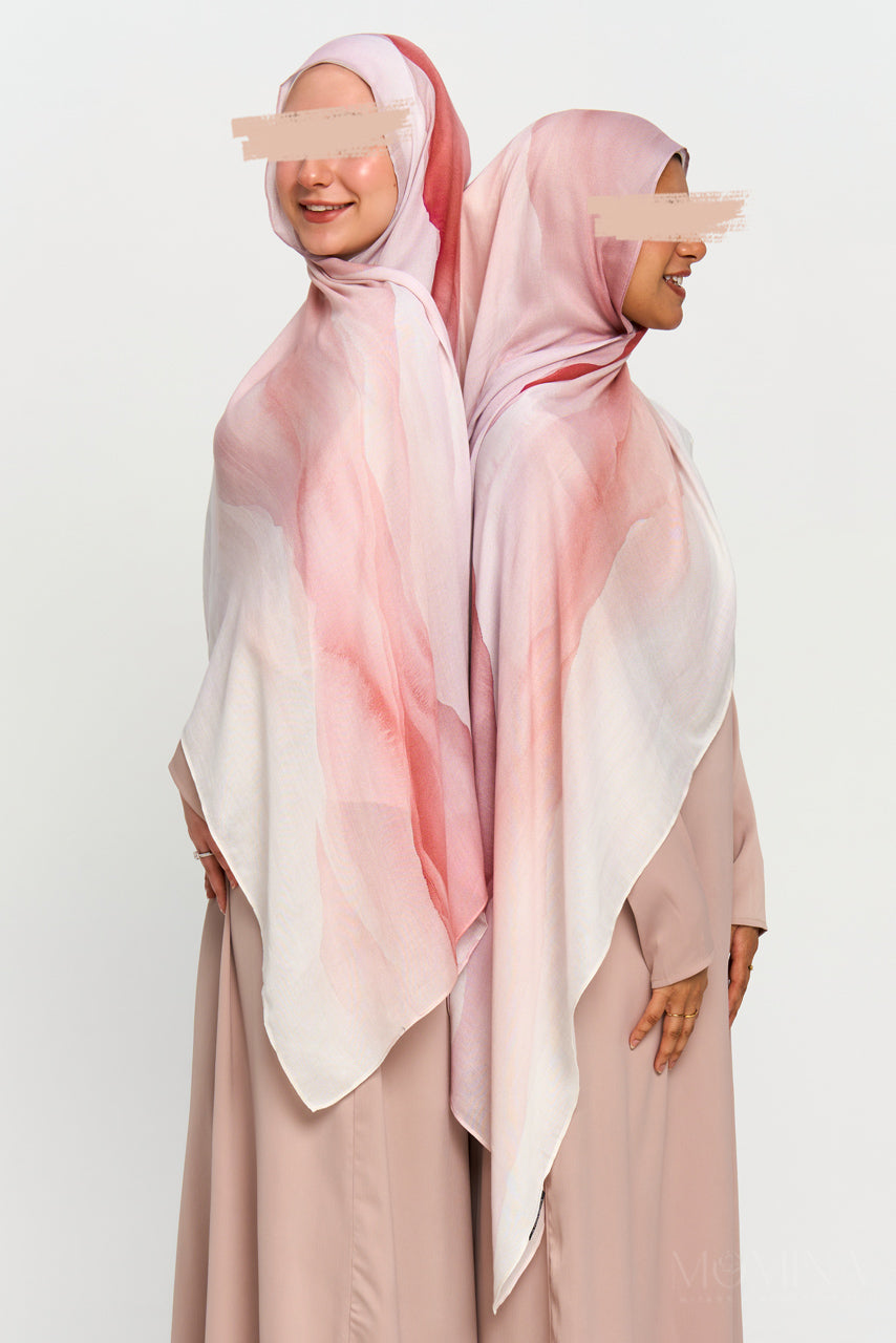 Two models wearing a blush pink watercolor-style printed modal hijab with a soft matte finish.