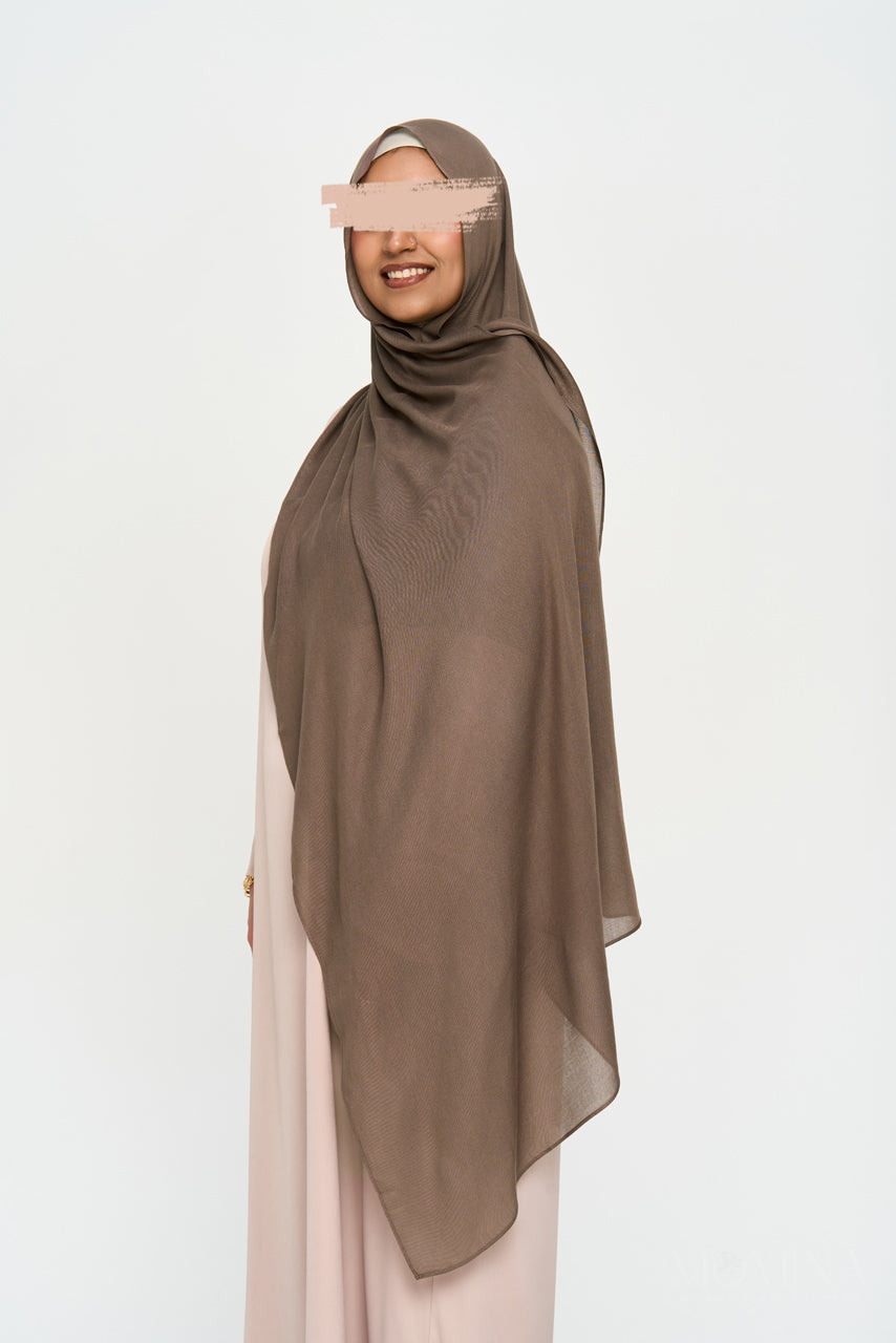 Full shot of a muslim woman wearing a brown modal hijab on a white background by Momina Hijabs