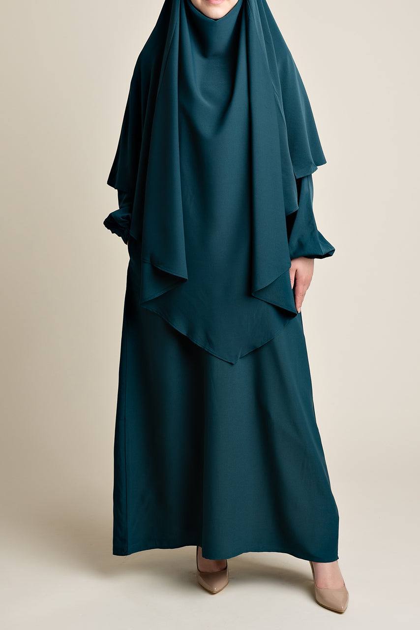 A front facing photograph of a female model wearing a teal matching abaya and khimar set from Momina Hijabs