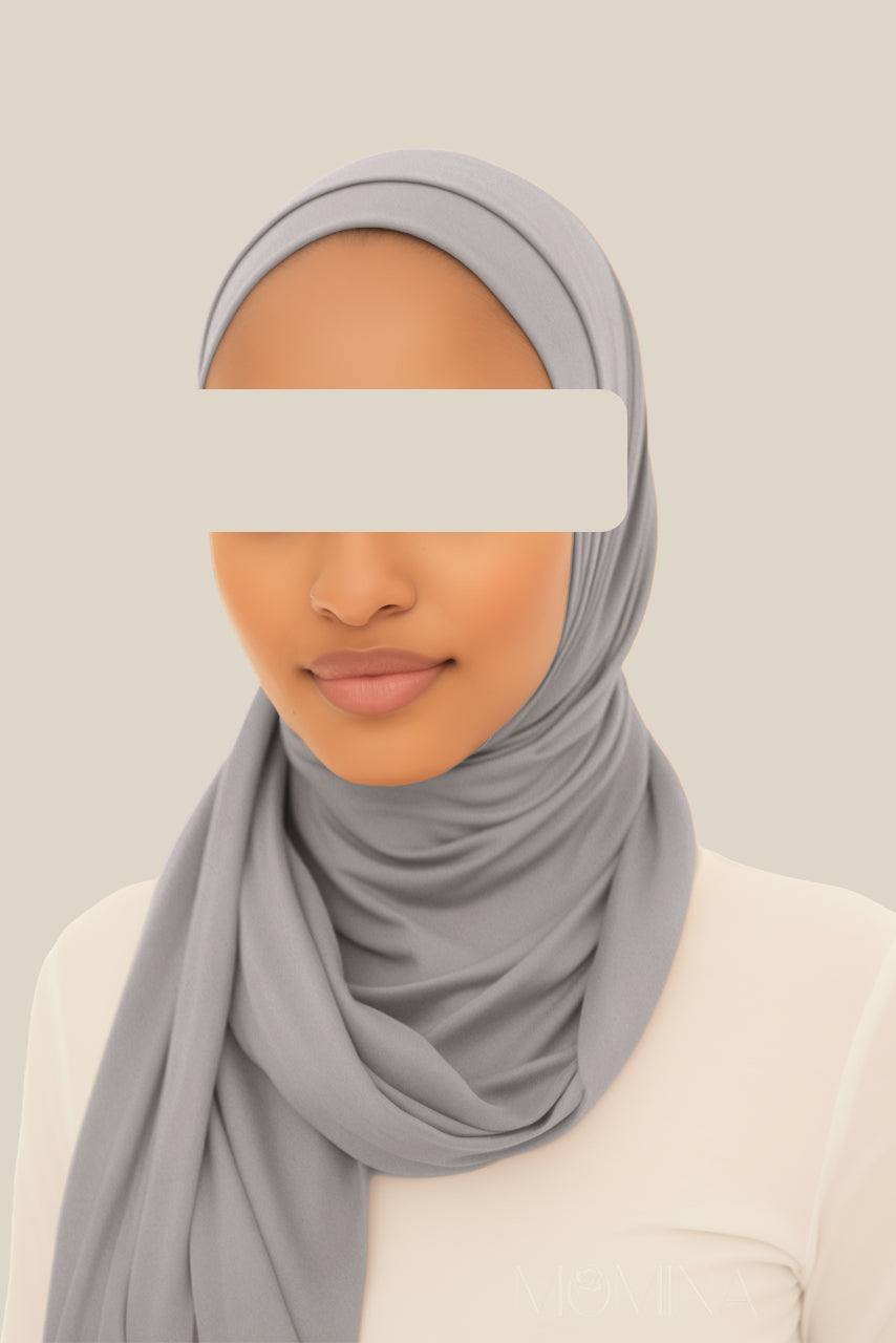 A woman wearing a medium gray matching jersey hijab and undercap set by Momina Hijabs.